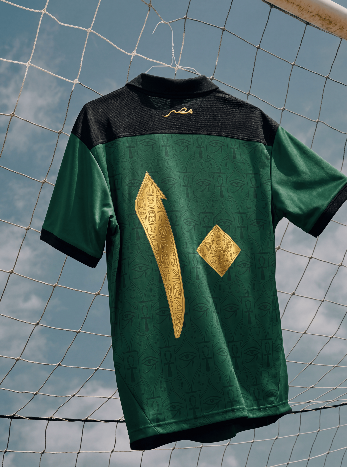 Green and black sports jersey with gold designs hanging against a netted background